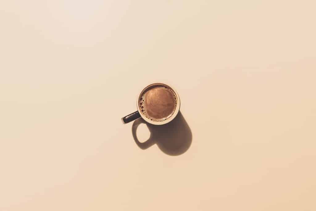 Kaffeetasse auf hellem Hintergrund, Schatten sichtbar.